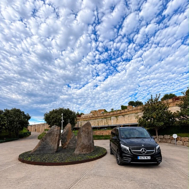 Mercedes-Benz V-Class negra de Black Button estacionada frente a un edificio de piedra en Esperit Roca bajo un cielo con nubes